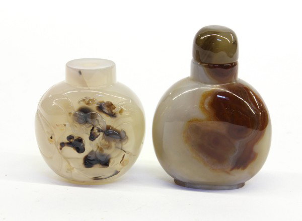 Two Chinese Agate Snuff Bottles: (Lot of 2) Chinese agate snuff bottles, each of flattened ovoid shape, the first of translucent gray hue and carved with a sage, attendant and lingzhi picked out from dark brown inclusions, reversed b