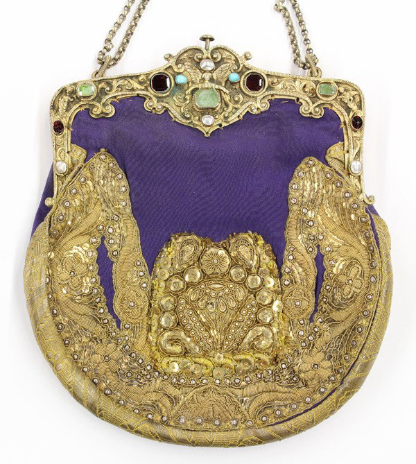 Gem set embroidered evening bagYellow gold intagl: Embroidered evening bag, in purple cloth, gold brocade, gilt and silver, accented across the top with garnets, blister pearls, turquoise and beryl gem stones. Having a silver chain handle