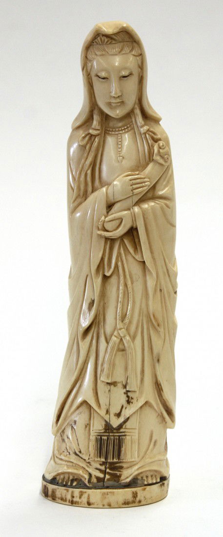 Chinese Ivory Guanyin Figure, Republic: Chinese tinted ivory figural carving, Republic period, depicting Guanyin standing in flowing robes and holding a wish-granting scepter to the front, the benevolent deity with an elaborate coiffure par