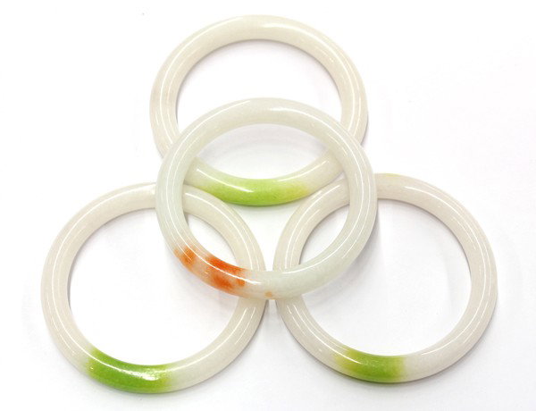 Collection of four white jade bangle bracelets: (lot 0f 4) white jade full bangle bracelets, each having a color spot accent