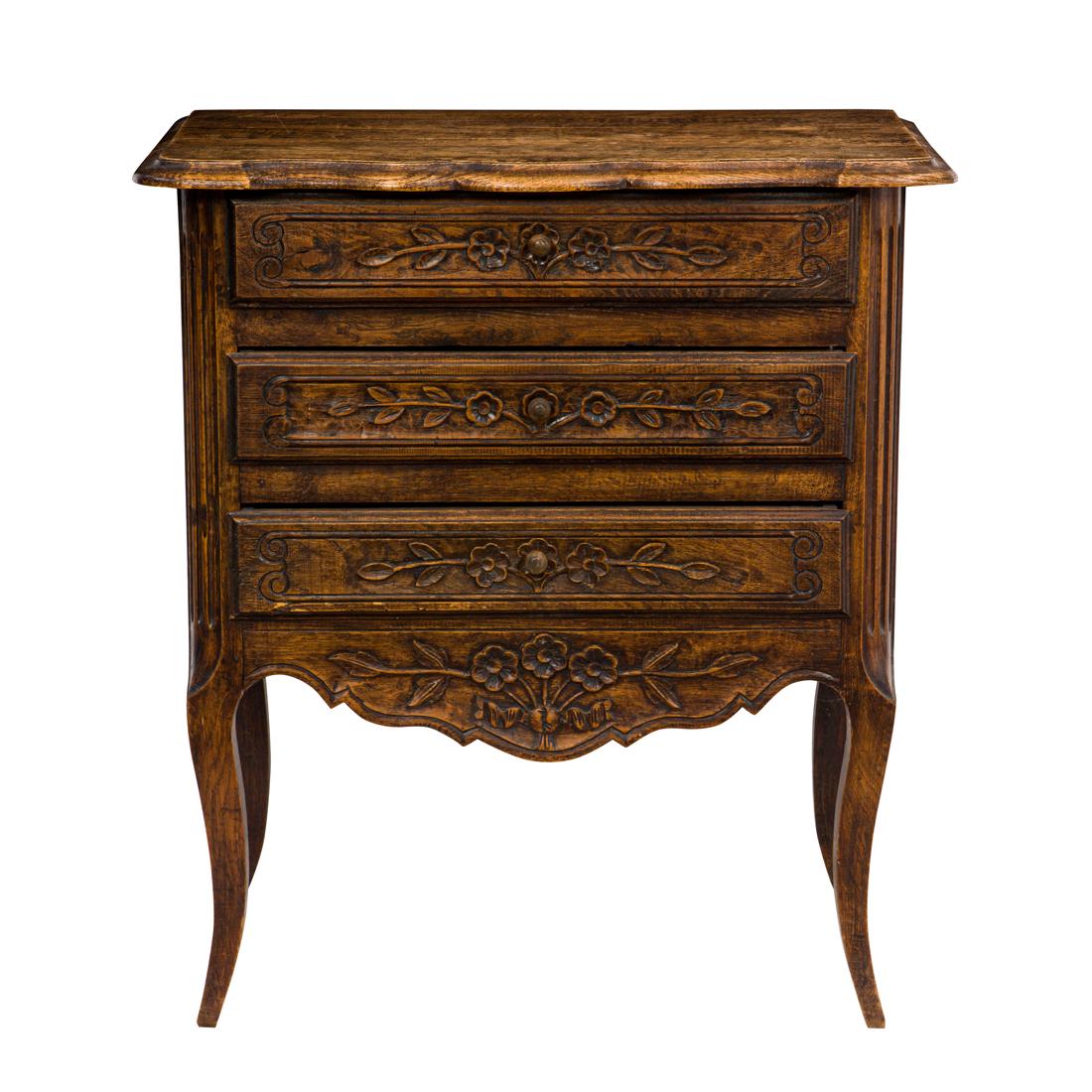 A Provincial three-drawer oak side commode: A Provincial three-drawer oak side commode, with a scallop top above the three drawer case, each with floral decorated fronts, and rising on outswept legs, 30"h x 28"w x 17.5"d