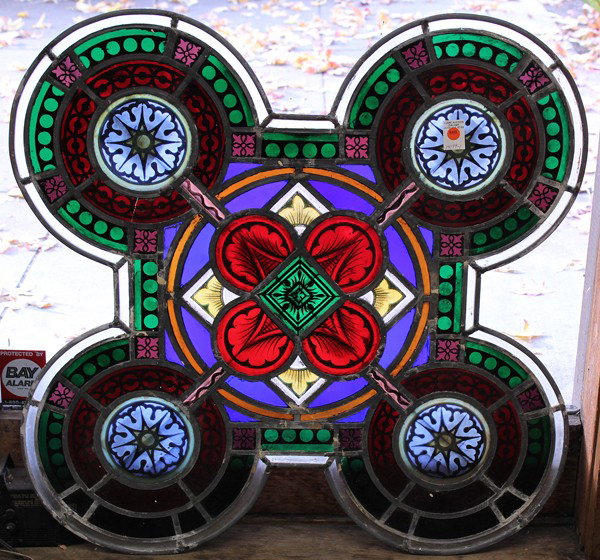 Stained glass window panel: Stained glass window, Massachussetts 1878 having a geometric decorated central panel flanked with circular borders, each centered with a rosette medallion, 34'' square, Provenance: From a Methodist Ch