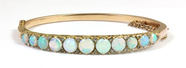 Opal diamond side hinged bangle bracelet: Opal and diamond detailed side hinged bangle bracelet, with safety chain; of 14k yellow gold, having opals and rose cut diamonds. Total bracelet weight 16.3 grams