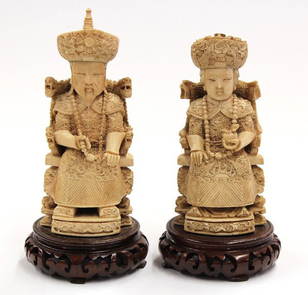 Pair of Chinese Ivory Emperor/Empress Figures: Pair of Chinese small tinted ivory emperor and empress figures, each seated on an elaborate throne and wearing brocade-patterned robes, the emperor with a short beard and shown toying with his long Ma