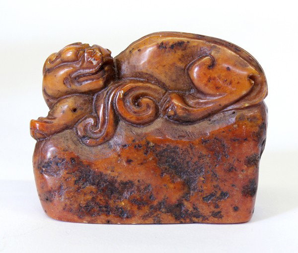 Chinese Soapstone Seal w/Dragon Finial: Chinese carved soapstone seal, fashioned with a recumbent chilong perched on a plinth, the base with three seal script characters 'xie chun yuan', the caramel-hued matrix mottled with dark inclusions,