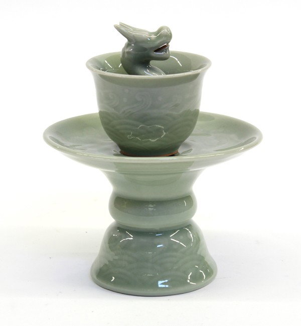 Chinese Celadon Glazed Porcelain Puzzle Cup/Stand: Chinese celadon glazed puzzle cup and stand, the deep cup molded with low relief wave pattern and centered by a three-dimensional dragon rising up from the center, the bottom pierced to allow the liqu