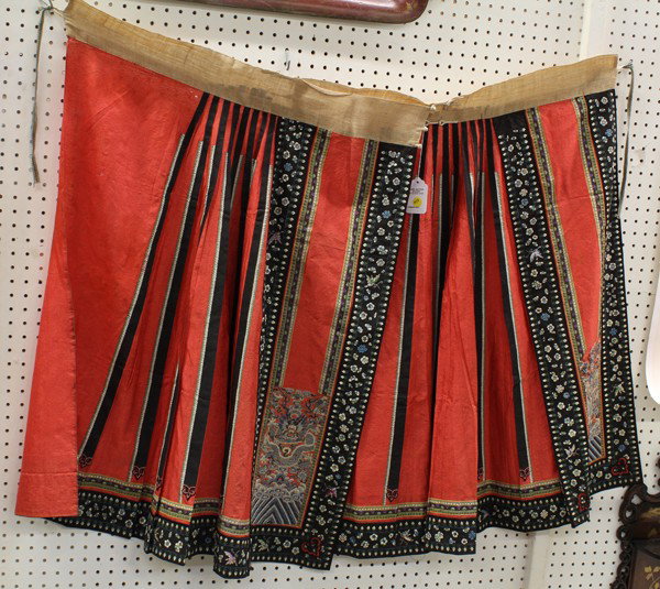 Chinese Woman's Silk Skirt: Chinese woman's red ground silk two panel skirt, the bright red ground with a damask pattern of lotus and Buddhist treasures, accented with black ribbon trim embroidered with flowers and butterflies, 