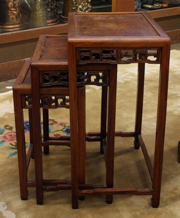 Chinese Nesting Tables: Set of three Chinese wooden nesting tables, each inset with a burlwood floating panel to the top, the apron pierced with flowers bracketed by scrolling tendrils, all raised on slender square supports 