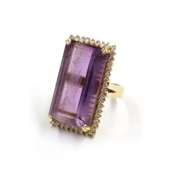 Amethyst diamond yellow gold ring: Amethyst and diamond ring; of yellow gold (stamped) 18k, having an elongated emerald cut amethyst and (48) round full cut diamonds weighing 0.75 ct. Total ring weight 16.0 grams. Ring size 6.5