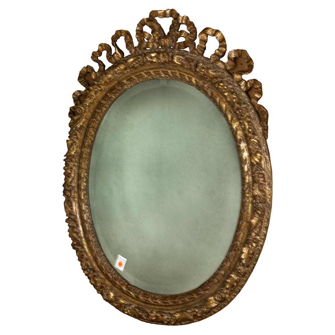 Rococo style giltwood mirror: Rococo style giltwood mirror, having a ribbon carved crest, above an oval beveled looking glass, 36.5"h x 28.5"w