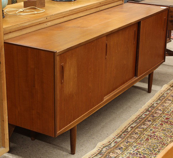 Danish teak sideboard: Mid Century Danish teak sideboard, having a rectangular case with three sliding doors opening to a partial fitted interior and rising on tapered legs, 30''h x 71''w x 16''d