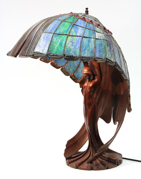 Art Nouveau style lamp: Art Nouveau style leaded glass table lamp, the shell form shade executed in geometric panels centered with a jewelled glass frieze, above a three light cluster rising on a patinated metal standard dep