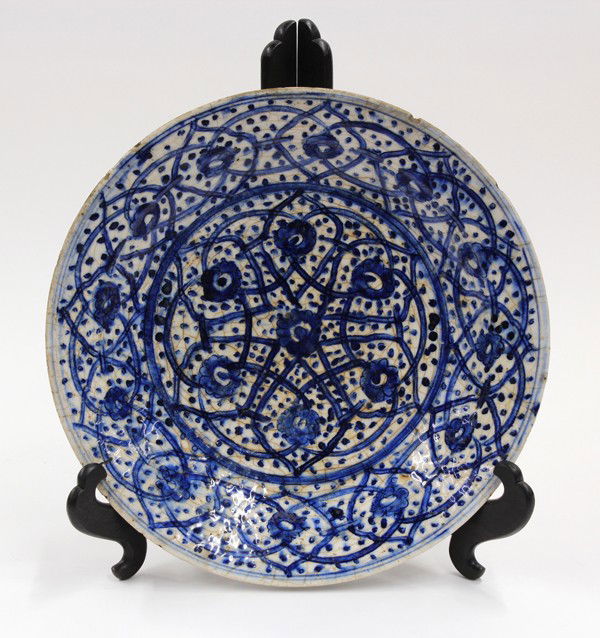 Islamic Blue-and-White Ceramic Plate: Islamic blue-and-white decorated earthenware dish, probably 15th-16th century, the interior well painted in cobalt blue with seven blossoms outlined in linked petal-shaped reserves on a blue stippled