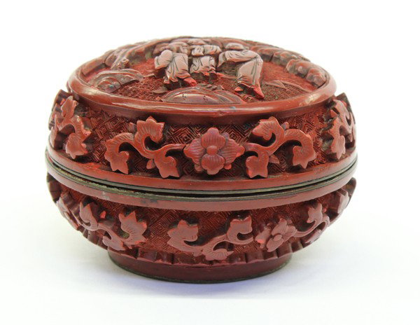 Chinese Cinnabar Lacquer Box: Chinese cinnabar lacquered circular box, the lid carved with an elderly scholar and friends on a river bank under a gnarled pine tree, the sides featuring blossoms and scrolling tendrils set against a