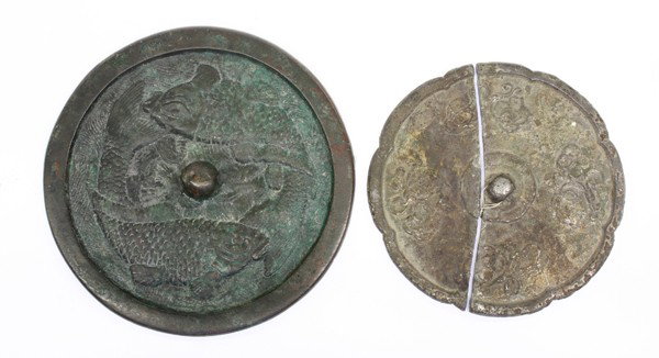 Two Chinese Bronze Mirrors, Fish, Flower: (Lot of 2) Chinese bronze mirrors, one of circular form cast with a pair of fish amid a wave patterned ground; the other of lobed shape and cast with four sprays of floral sprigs; together with labels