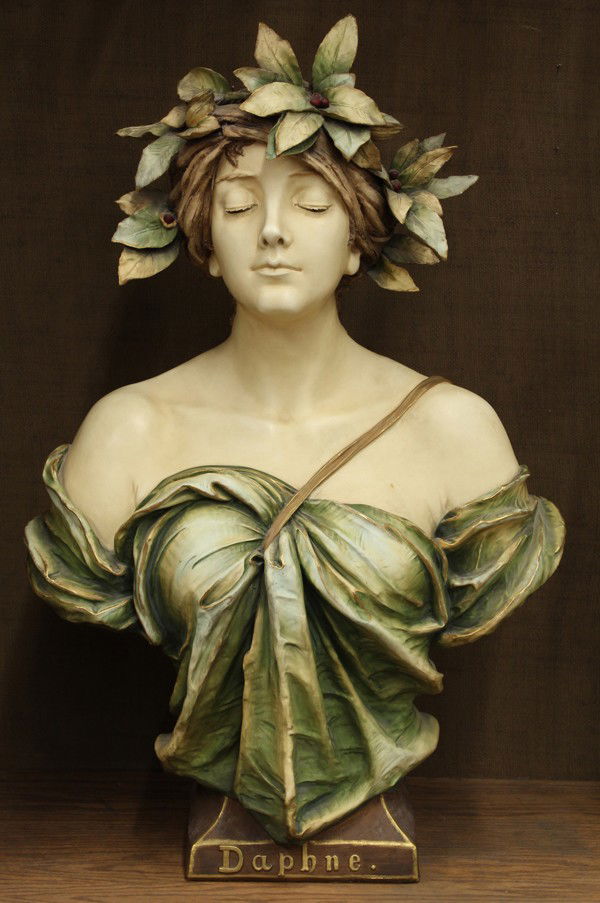 Amphora bust of Daphne: Ernst Wahliss earthenware bust of ''Daphne'', Austria circa 1900, the goddess crowned in a laurel wreath, with partially downcast eyes and draped in classical attire, rising on a square plinth with 'D