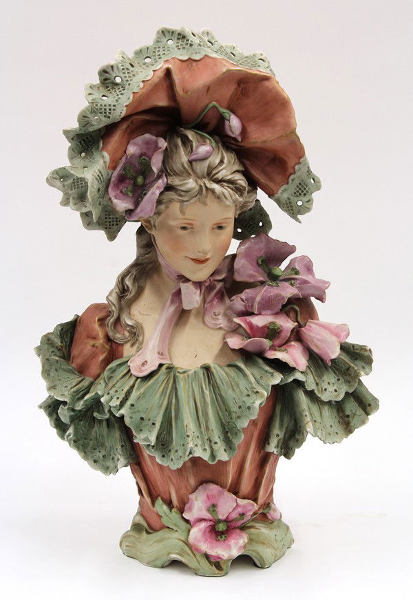 Royal Dux earthenware bust: Royal Dux, Bohemia, bust of a young maiden, modeled in the Baroque taste, wearing a lace hat and gown accented with flowering poppies, and rising on a footed base, 21'' h