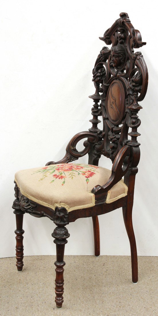 Continental carved hall chair: Continental carved walnut hall chair, circa 1860, having a bacchanalian figural reserve surmounting the oval medallion, the sides having floral sprays, and rising on turned legs, 48''h