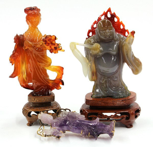 Three Chinese Carved Stone Figures: (Lot of 3) Chinese figural stone carvings, including: an amethyst maiden, currently mounted as a brooch in gold fittings; a chalcedony celestial beauty clutching a floral sprig; and Budai holding a fl