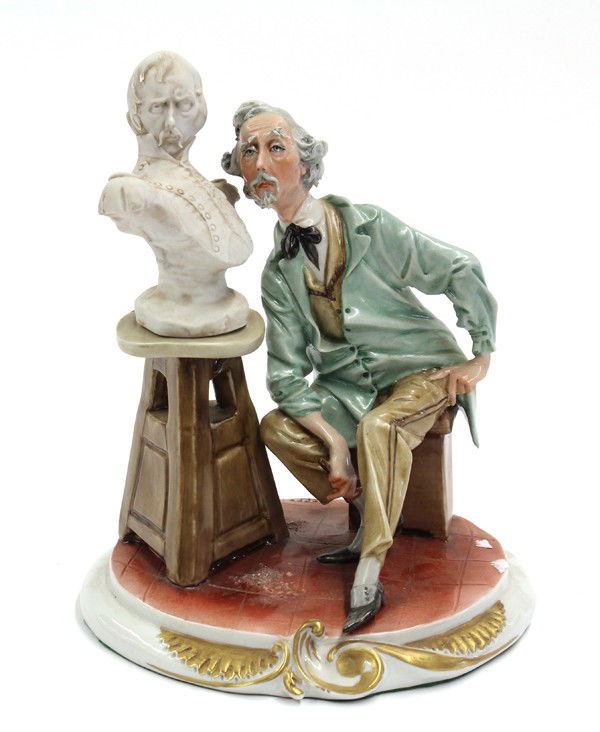 Capodimonte porcelain figure: Capodimonte porcelain sculptor depicted seated on a stool and leaning towards a bust of himself, mounted on a circular base, marked overglaze with crowned K King's Capodimonte Made in Italy, 9.5''h