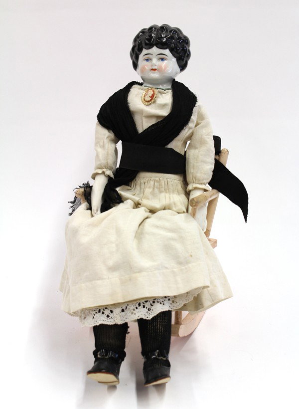 Doll and rocker: Victorian China head low brow doll on a cloth body with bisque forearms and hands, 24'' together with a doll rocker (losses and repairs to left hand)