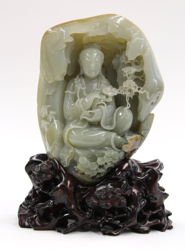 Chinese Jade Boulder, Guanyin: Chinese jade (nephrite) boulder, well carved as a grotto framing a benevolent Guanyin seated in lalitasan and displaying a gnarled ruyi scepter in her hands, the background accented with a viewing pav