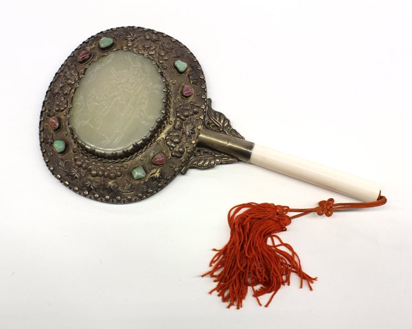 Chinese Mounted Mirror with Jade Plaque: Chinese silver mounted mirror with an inlaid jade plaque, the celadon jade plaque carved with a scholar standing beside a gnarled tree carved in low relief, set within a silver repousse frame of flora