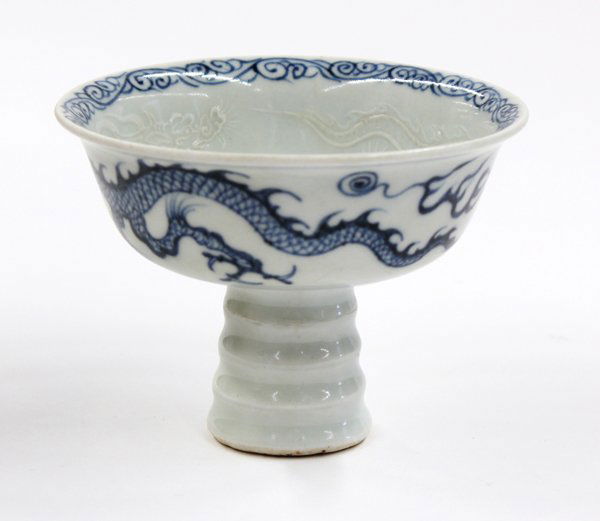 Chinese Blue-and-White Porcelain Stem Cup: Chinese underglaze blue porcelain stem cup, the exterior encircled by a long writhing cobalt blue dragon in pursuit of a jewel, the well centered with a floral spray and encircled by a pair of white d