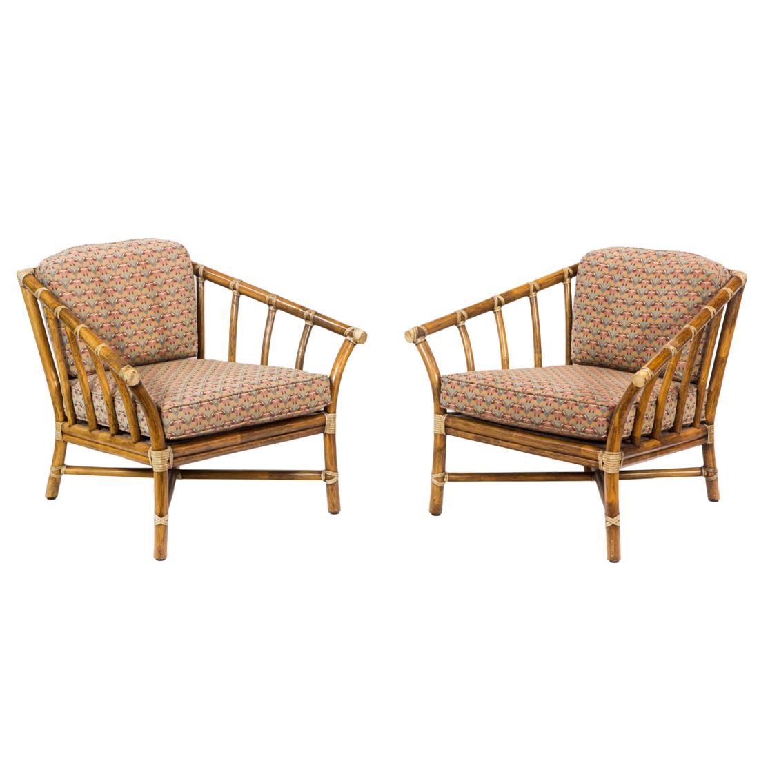 A pair of deep McGuire lounge chairs: A pair of deep McGuire lounge chairs, each with a soft loose cushion seat and back, with a rattan frame with natural support banding, 28"h x 33"w x 27"d