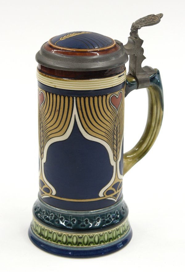 Mettlach German stein: Mettlach German 1/2 stein, executed in the art Nouveau taste, accented with heart shaped reserves centering the incised pulled feather design continuing to the graduated footed base, impressed mark, 8