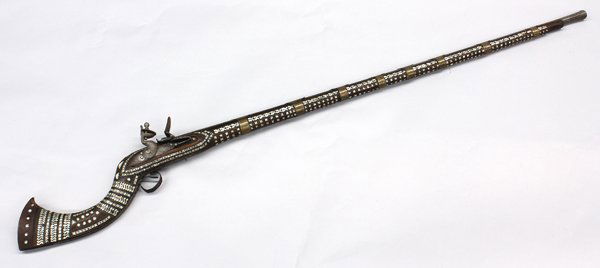 Afghan flintlock jezail long-barreled musket: Afghan flintlock jezail long-barreled musket, the 47'' barrel with a decorative chased design, and a flared muzzle with integral rear sight, retained by eight brass capucines, British lock dated 1807,