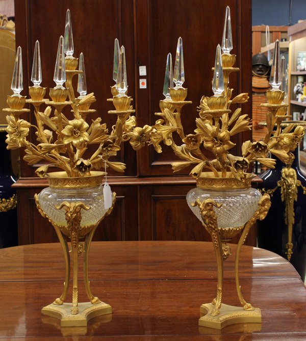 Louis XVI style candelabra: Pair Louis XVI style gilt bronze seven light candelabra, the faceted prism inserts surmounting the flowering lilly form supports continuing to the cut crystal urn form standard supported with gilt bro
