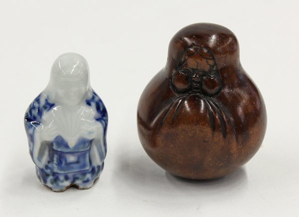 Two Japanese Netsuke, Okame, 19th Century: (Lot of 2) Japanese figural netsuke, the first of boxwood, 19th century, carved as Okame in the guise of a Daruma ningyo (doll), 1.8''; the second a 19th century Hirada porcelain toggle fashioned as O