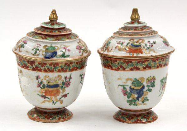 Chinese Thai-style Bencharong Porcelain Cups: Pair of Chinese Thai inspired bencharong enameled porcelain covered cups, 19th century, the exterior painted with the Eight Auspicious Buddhist Symbols accented with floral sprigs and ribbons below a 