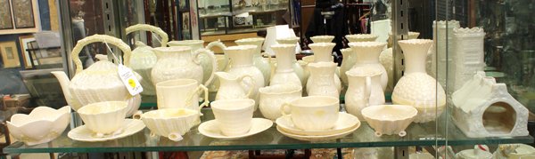 Belleek porcelain group: (lot of 70) Belleek Irish porcelain group consisting of teapots, cups, bells, vases, nesting dishes, figures of dogs and a wall pocket, with various marks, including green, black, blue, brown, and red