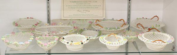 Belleek basket group: (lot of 13) Belleek woven porcelain baskets, mid 20th century through 2007, in assorted shapes including heart, oval and trefoil, some with handles and most with applied porcelain flowers, including 2