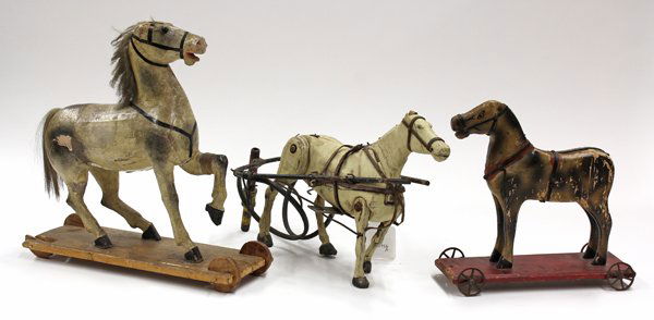 American Folk Art pull toys: (lot of 3) American Folk Art pull toys, each depicting a polychrome decorated wood carved stallion, two rising on a wood plank with casters, largest 14''h x 13''w, one marked S.A. Smith, Mfg Battlebor