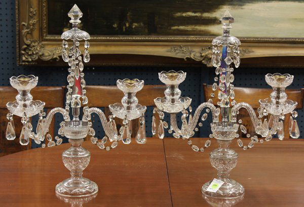 Crystal candelabra: Continental style crystal candelabra, the two arm fixture centered by the finial capped obelisk standard conjoined with crystal prism swags above an urn form standard rising on a circular base, 20''h
