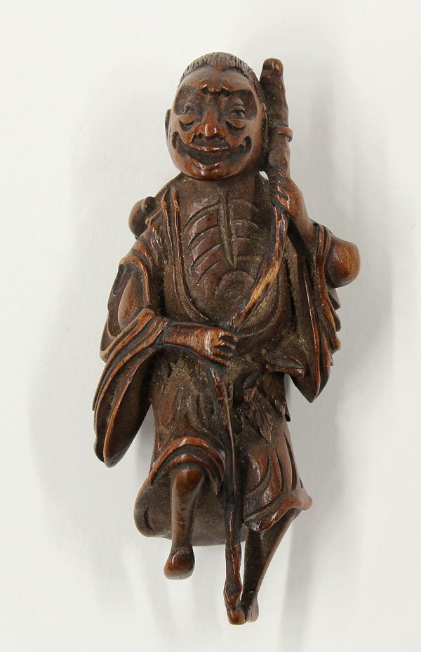 Japanese Boxwood Figural Netsuke, Edo: Japanese boxwood figural netsuke, Edo period, 18th/19th century, well carved as a dancing mendicant wearing a mugwort apron and cape over monastic robes open to reveal his emaciated chest, a long staf