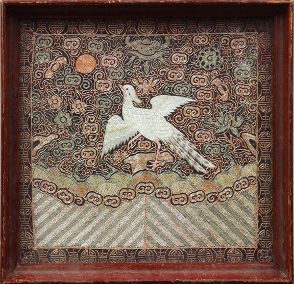 Chinese Civil Service Rank Badge: Framed Chinese rank badge/Mandarin square, featuring a white bird to the center, probably the paradise flycatcher, amid metallic couched flowers and clouds above rolling waves, all within a shou medal
