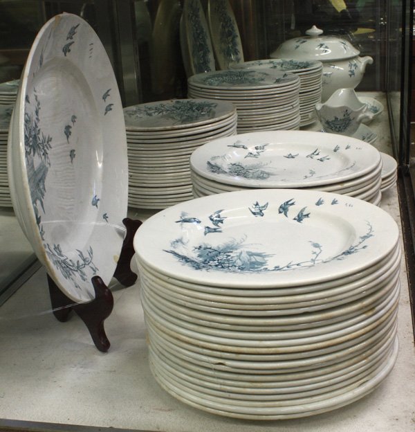 French Faience Table Service: French, late 19th century, faience table service with a transfer decorated country motif showing flowers, birds and a village landscape consisting of 38 9'' plates, 68 8.25'' plates, four soup bowls,