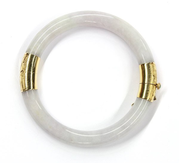 Jadeite hinged bangle bracelet: One jade side hinged bangle bracelet with 14K (stamped) yellow gold clasp and fittings, measuring 8.75'' around and 9.09 mm. in diameter.