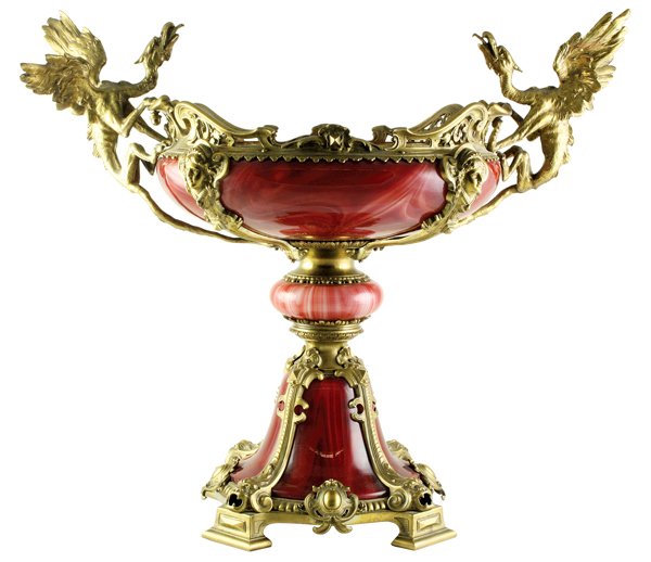 Continental ormolu mounted glass tazza: Continental ormolu mounted glass tazza, 19th century, having a blown glass body accented with gilt bronze mounts flanked with winged griffin handles, the ruby body encased with figural mounted support