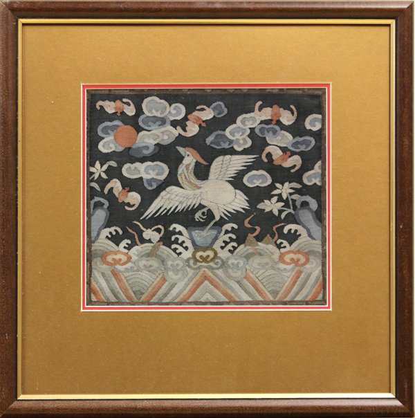 Chinese Civil Serice Rank Badge: Framed Chinese woven kesi civil service rank badge, Qing dynasty, the elegant bird with wings splayed and perched on a rock amid rolling waves, the blue sky decorated with auspicious bats and clouds, 