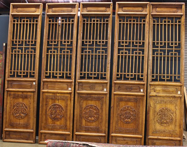 Five Chinese Wood Door Panels: (Lot of 5) Set of Chinese wooden door panels, each with a lattice panel above a lower panel carved with a medallion featuring auspicious characters along with dragons or bats within a key-fret border,