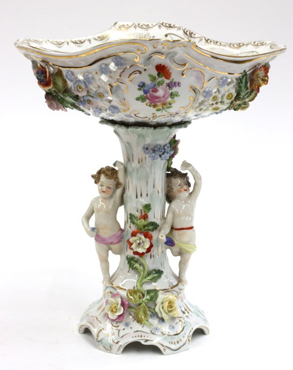 Dresden figural compote: Dresden porcelain figural compote, the reticulated bowl above the naturalistic standard flanked with playful putti and rising on a Rococo style base, marked on base, 11.5''h x 10''w (lacks central bol