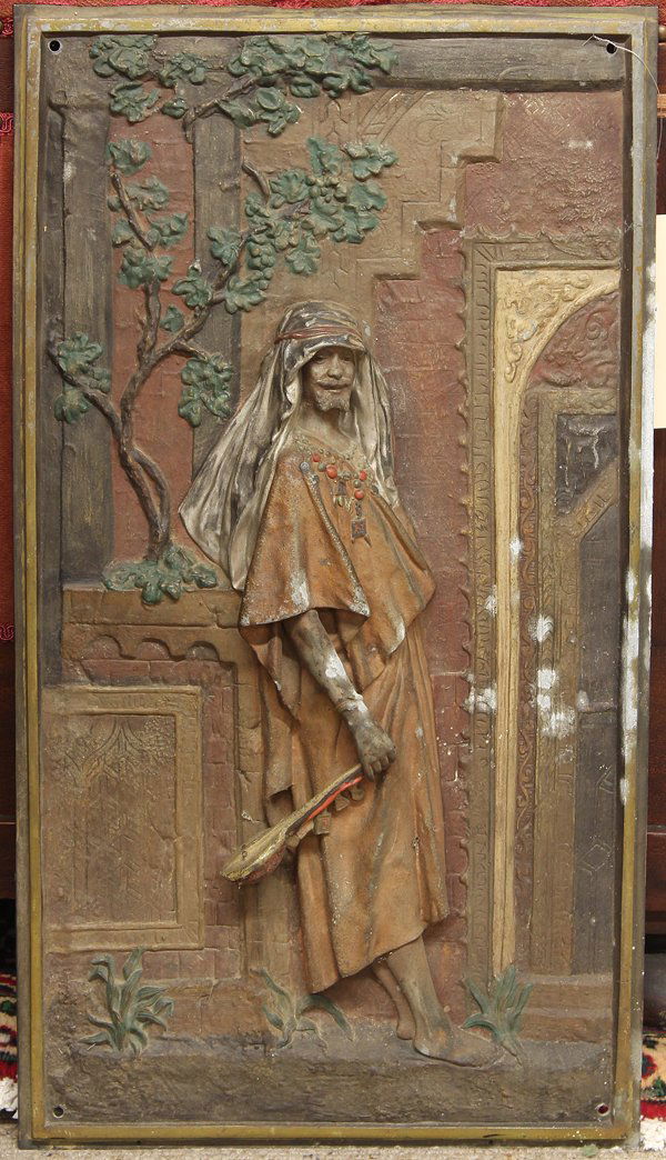 Cold painted metal plaques, Hottot: (lot of 2) Cold painted metal bas relief plaques, after Louis Hottot (1834-1905), each depicting a genre scene, one a maiden bearing an amphora near a well, her eyes gazing outward, one depicting an A