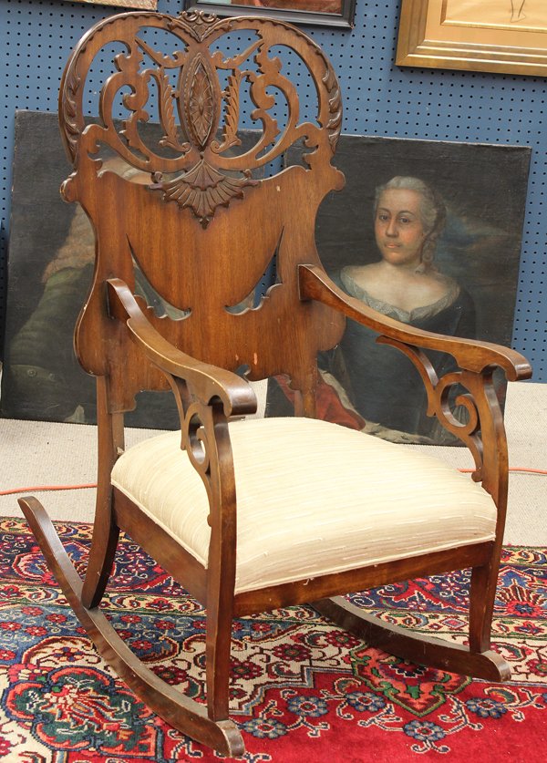 Victorian walnut rocking chair: Victorian walnut rocking chair circa 1890, having a scroll carved back of shield form centered with an applied medallion, the arms with pierce carved bracket returns continuing to the square legs, 42'