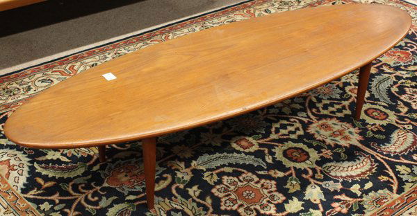 Danish Modern surfboard table: Danish Modern teak coffee table, the surfboard form having a rounded edge and rising on turned tapered legs, 13''h x 66''w x 22''d