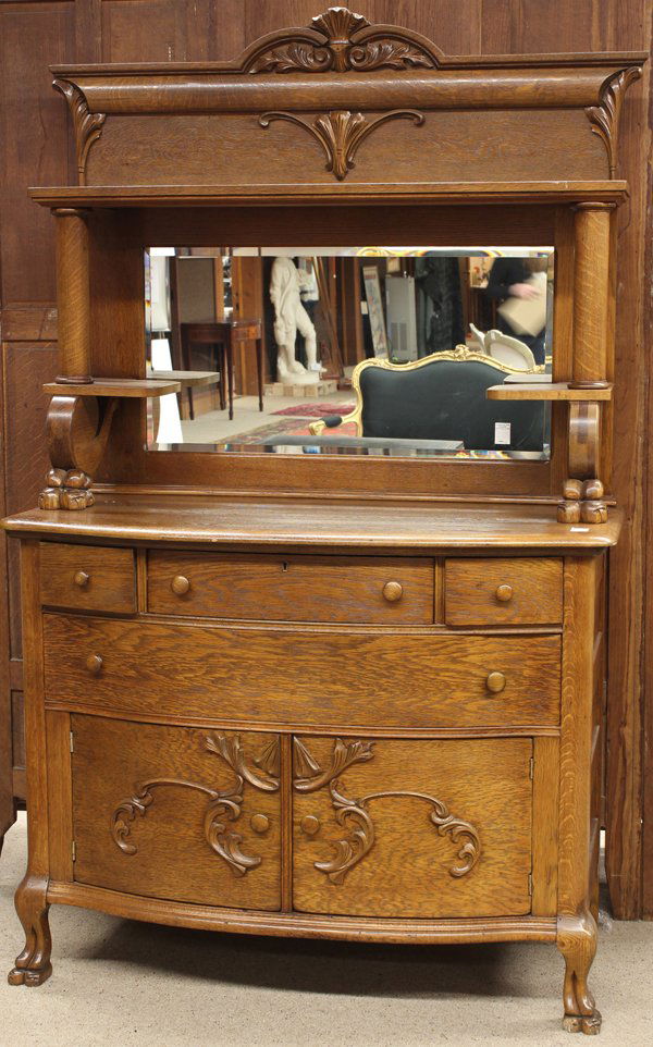 American Golden Oak sideboard: American Golden Oak sideboard circa 1910, the hooded superstructure with columnar supports terminating at the stylized paw feet above the lower case having applied floral detail and rising on cabriole